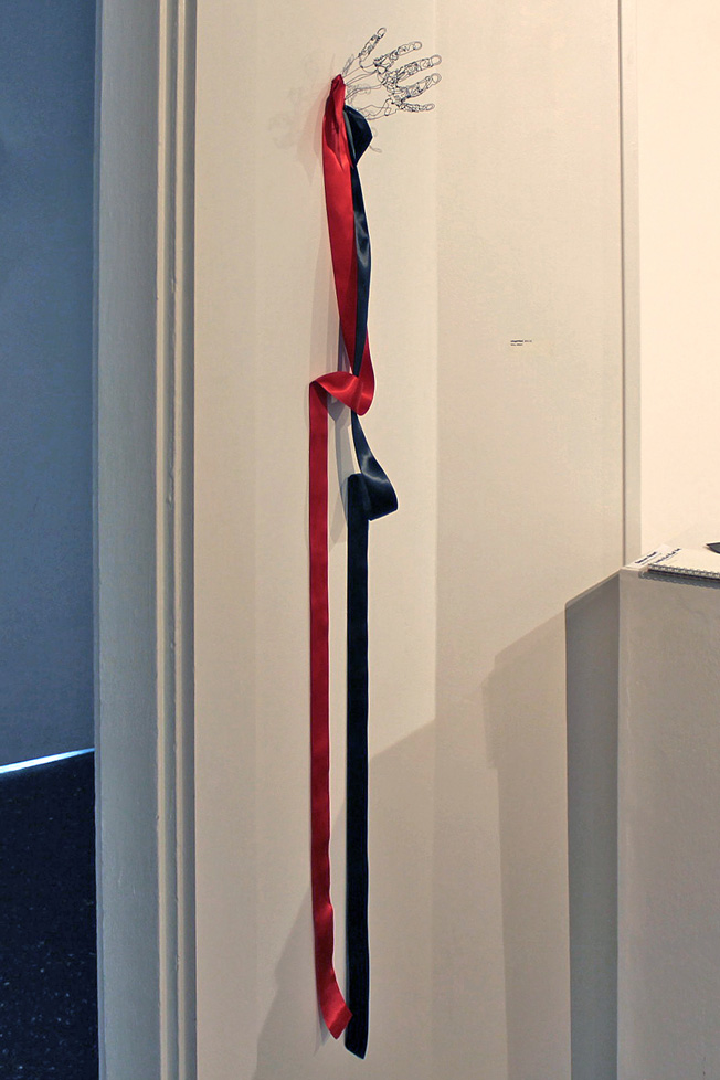 wire hand sticking out of wall with red and black ribbon
