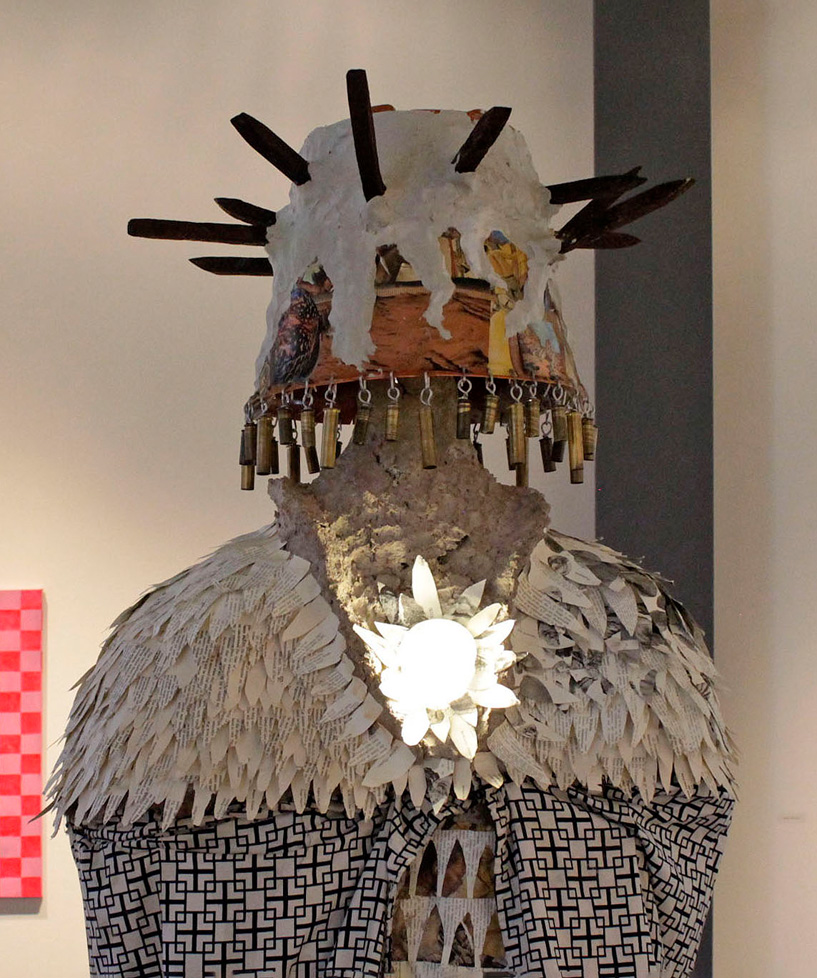 sculpture: life-size figure with flowing robes, spiked head, and glowing heart