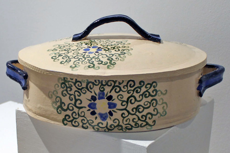 ceramic casserole dish, tan with central floral design of blue flower and swirling green vines, blue handles on sides and lid