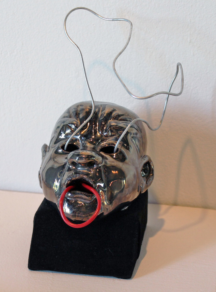 ceramic head with wire emanating from eyes and mouth