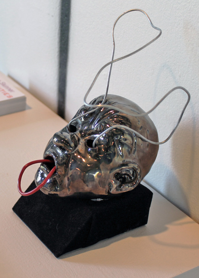 ceramic head with wire emanating from eyes and mouth