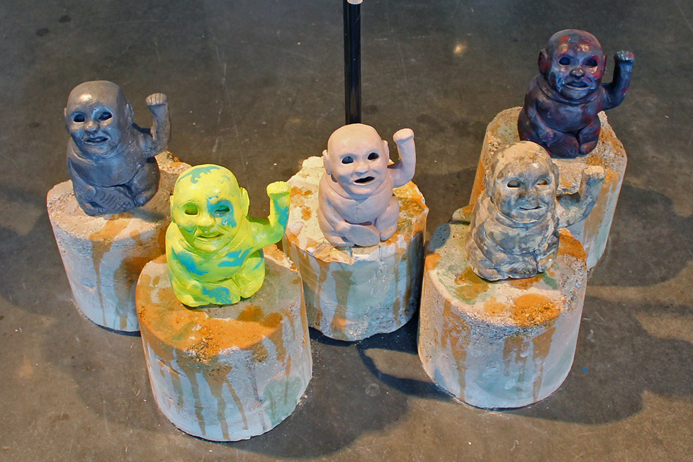 5 plaster babies in different colors on plaster cylinders