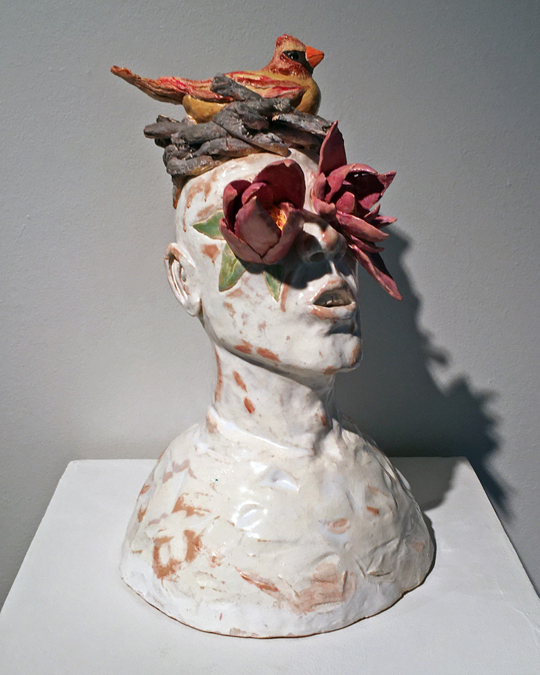 ceramic bust with protruding flower eyes and bird nesting atop