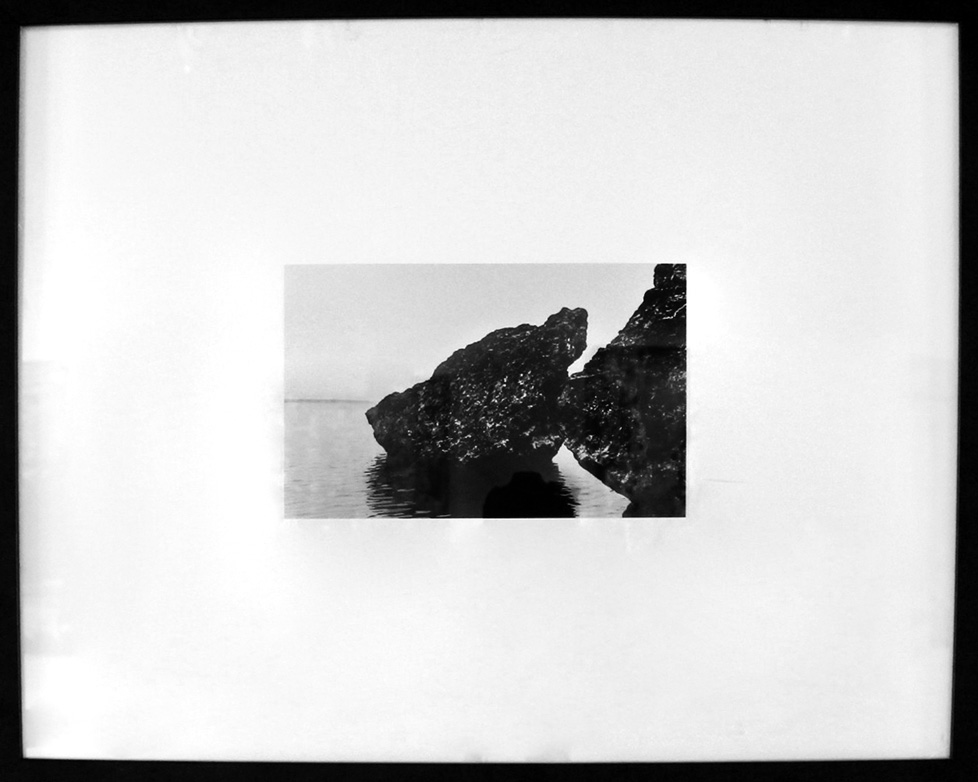 framed black and white photo of large rock in water