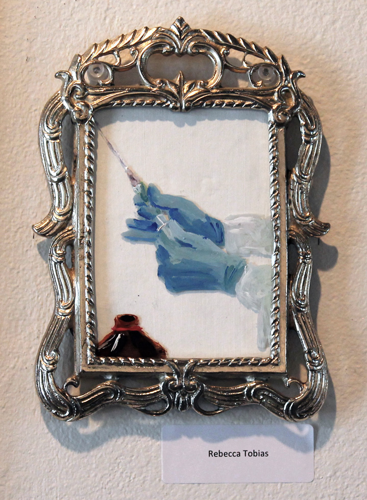 small framed painting of blue gloved hands with syringe