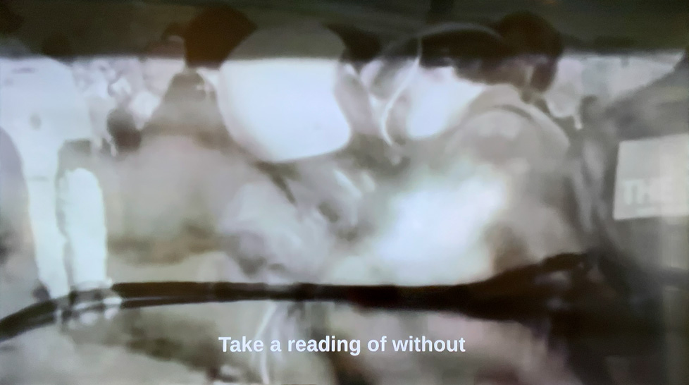 video still: B&W images with caption "Take a reading of without"