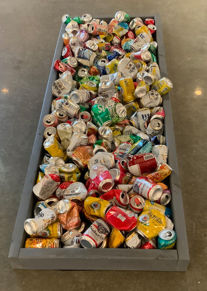 beer cans in a wooden frame on the floor