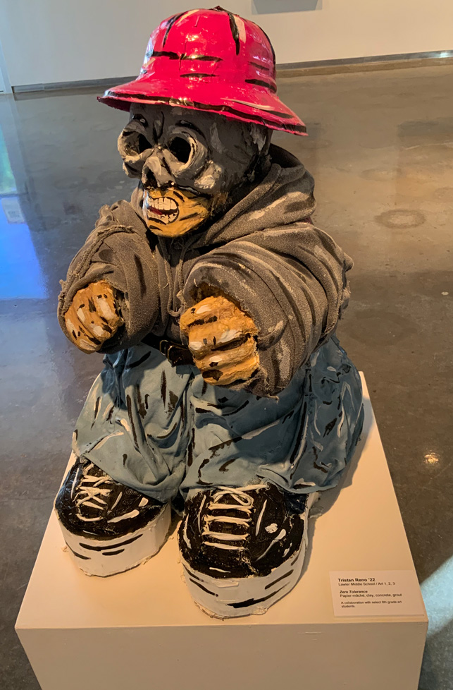 sculpture of short figure with pink bucket hat, goggles, and a backpack