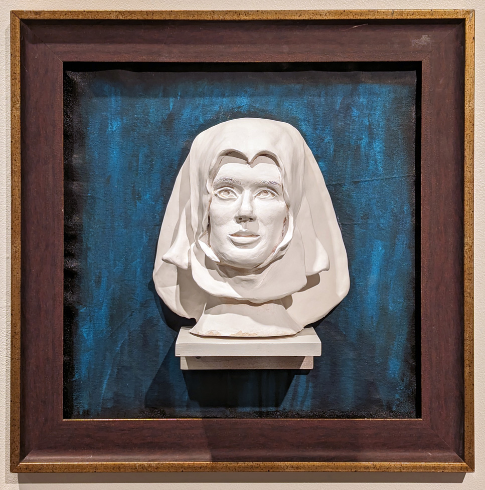 ceramic bust on small shelf mounted inside frame with blue ground