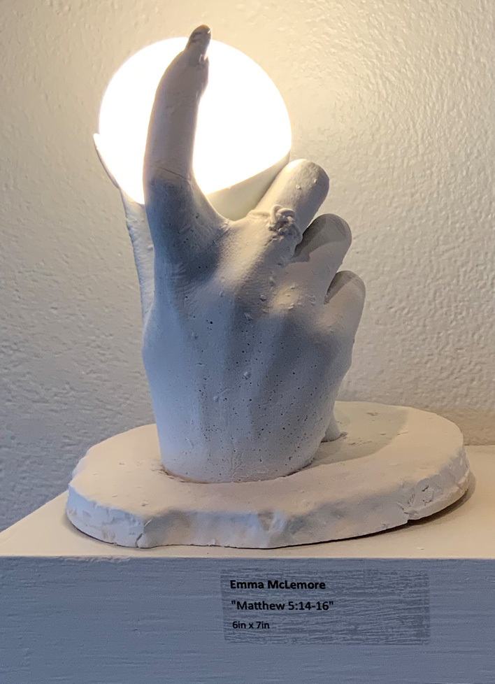 sculpture of hand holding lightbulb, lit