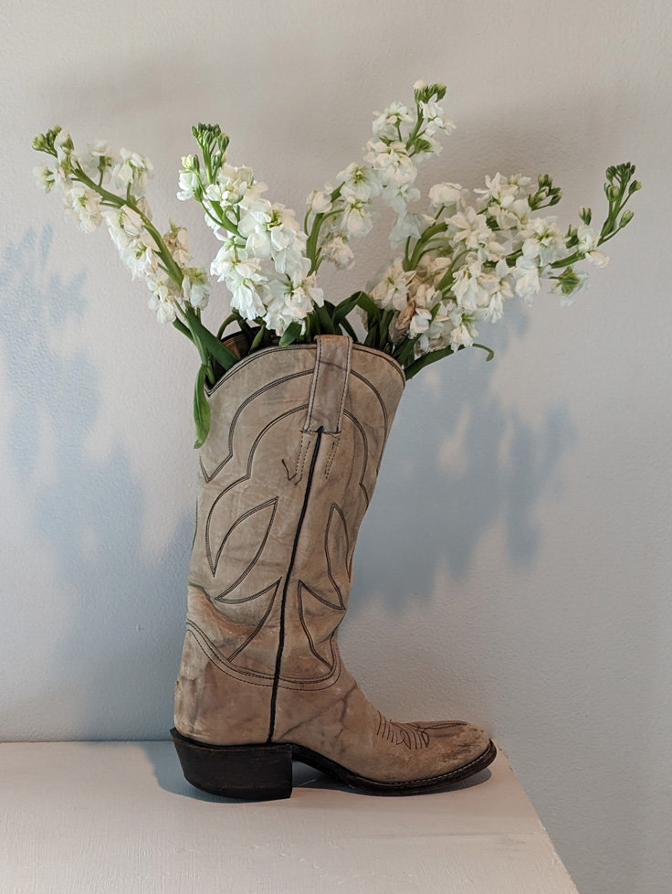 light brown cowboy boot, used like a vase holding white flowers