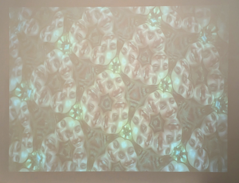 kaleidoscopic image of woman's face projected on wall (photo of video)