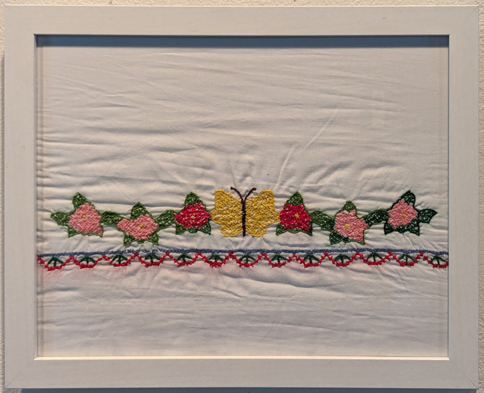 framed embroidery of a butterfly with flowers on either side in a row