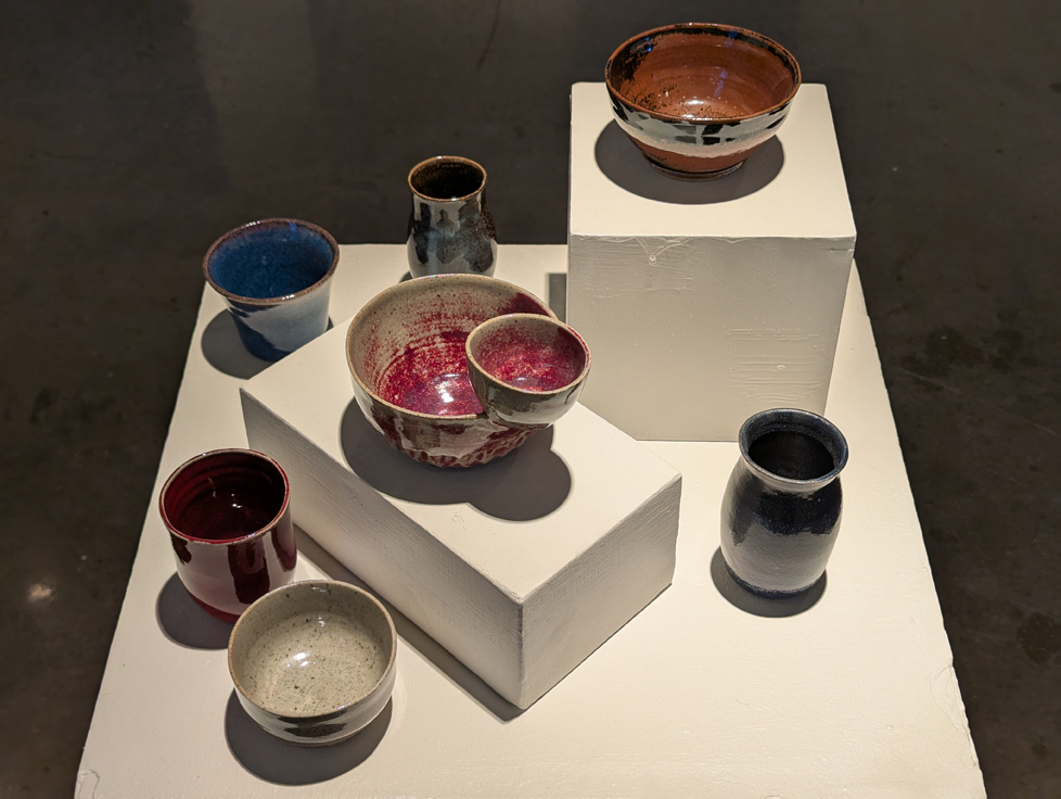 7 bowls glazed in different colors aranged on a pedestal