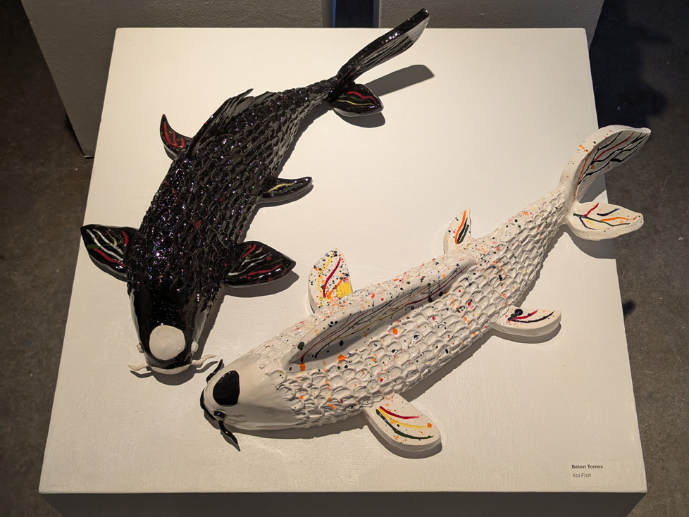 2 large ceramic koi on low pedestal, one black, one white