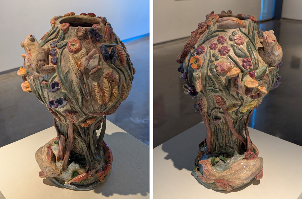 ceramic vase shaped something like a tree, but covered with plants and small animals like a frog, a fish, and a butterfly