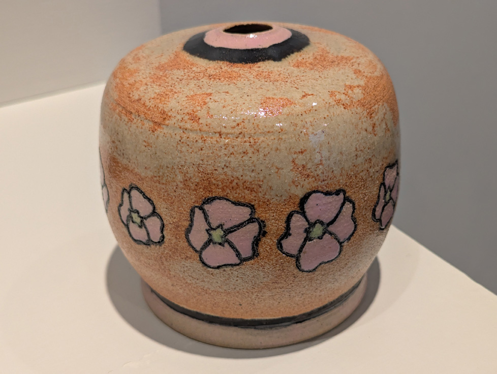 round vase with narrow opening, tan-orange with a ring of pink flowers painted