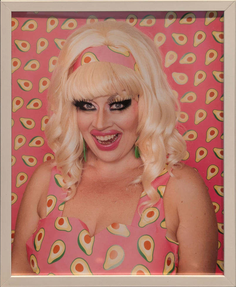 blonde woman in dress with avocado print that matches background wallpaper