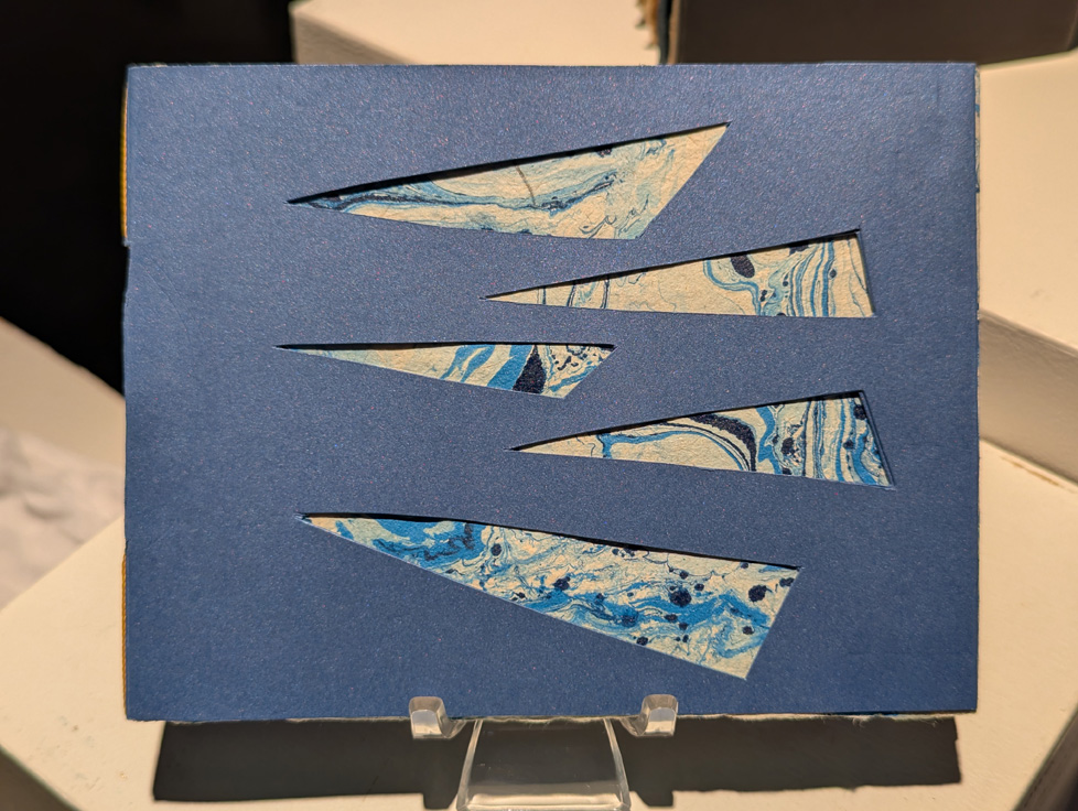 artist book: blue cover with triangular windows revealing marbled paper
