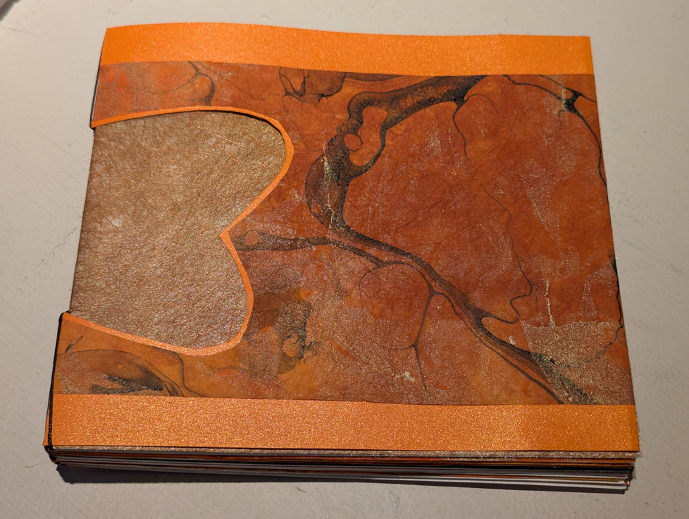 artist book in orange with wing-shaped window in cover