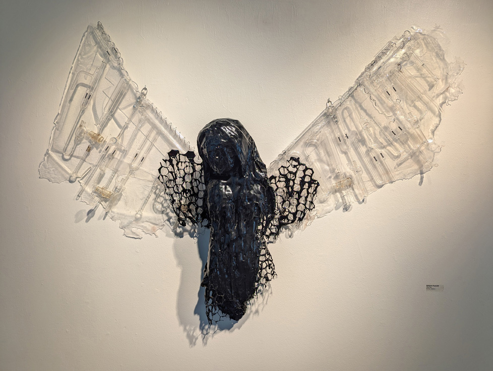 wall sculpture: tar covered figure with wings of scientific glass and clear plastic