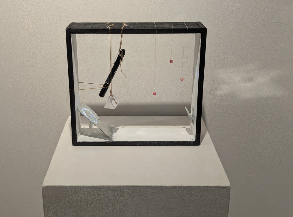 box containing suspended flashlight, prism, and beads