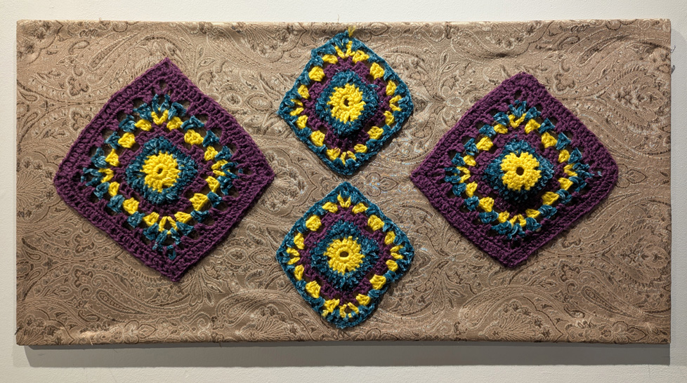 purple, yellow, and blue potholders attached to stretched taupe fabric