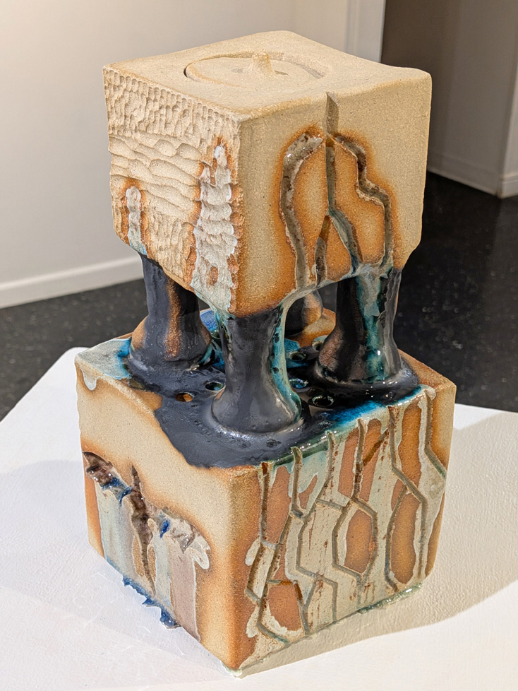 abstract ceramic sculpture on pedestal: 2 stacked cubes with four small columns between them