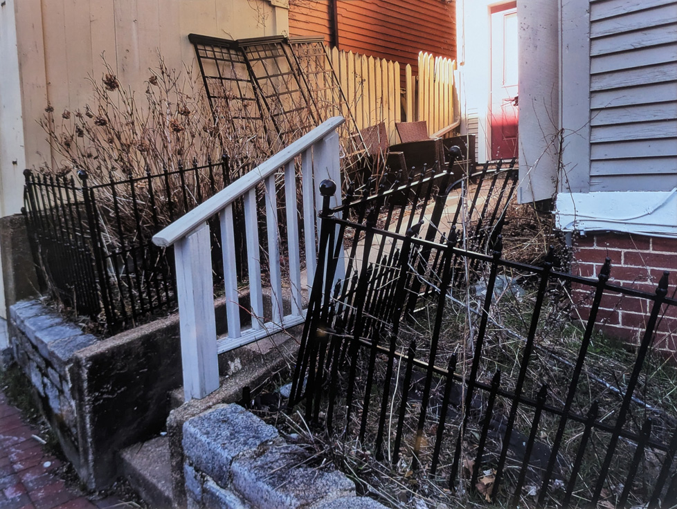 photo of white railing and black fence, leaning and bent