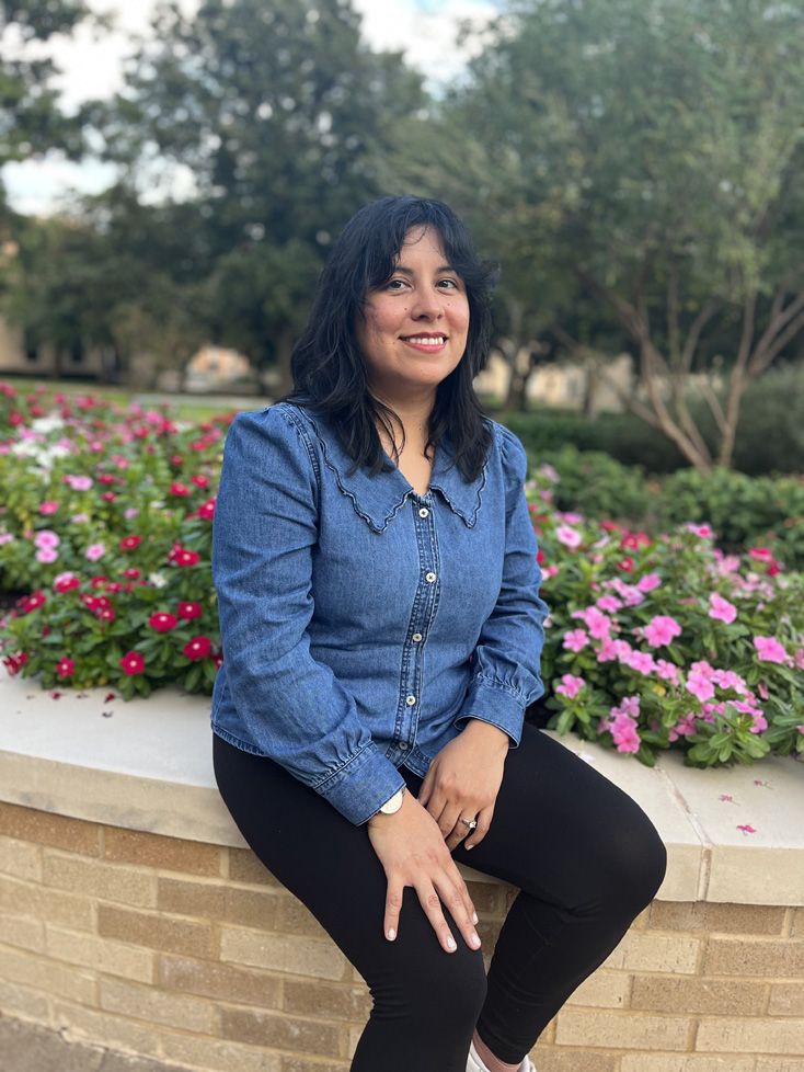 Andrea sitting by campus flower bed