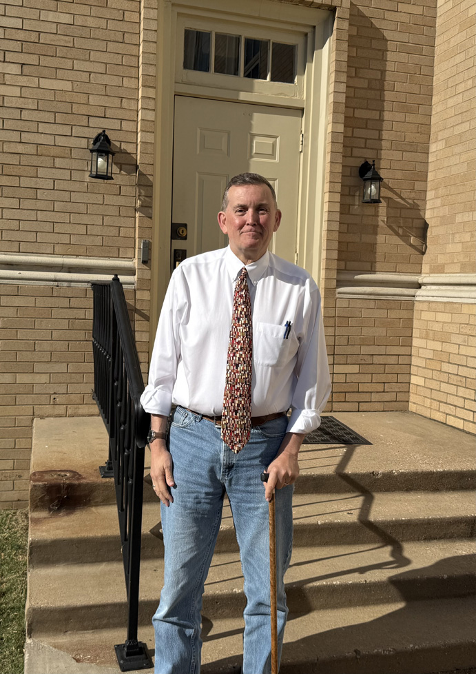 John Williams standing with cane by chapel door