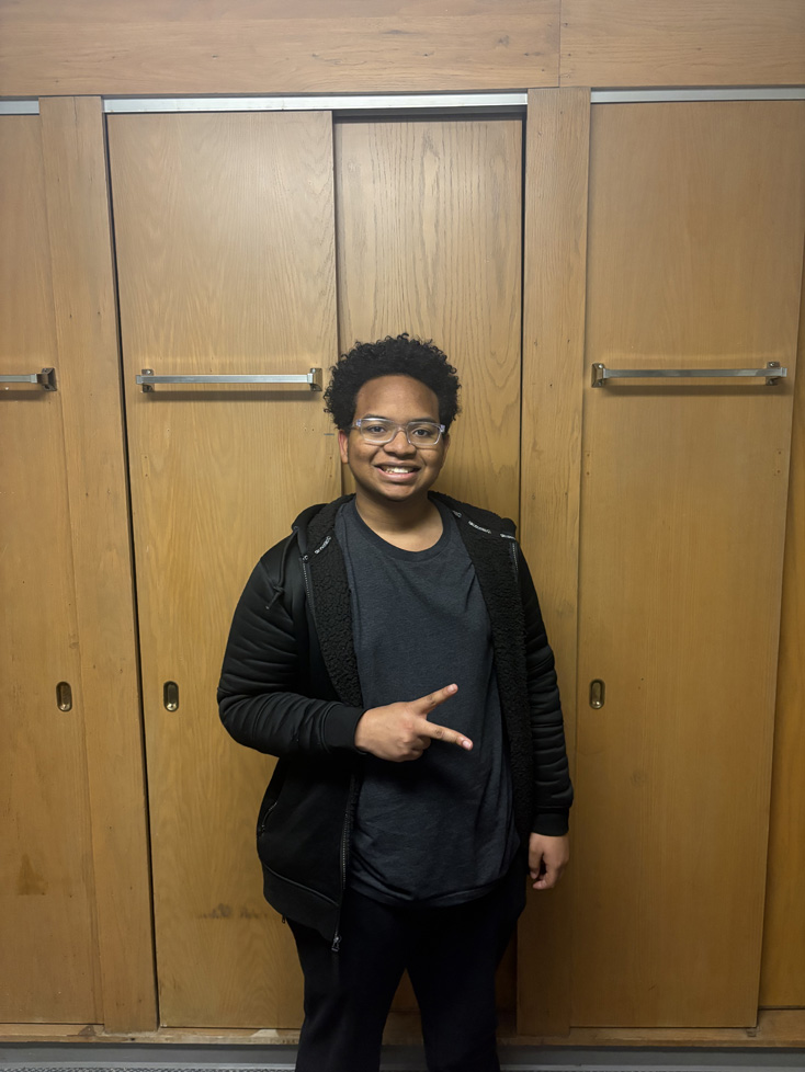 Bryce throwing peace sign against wood cabinets