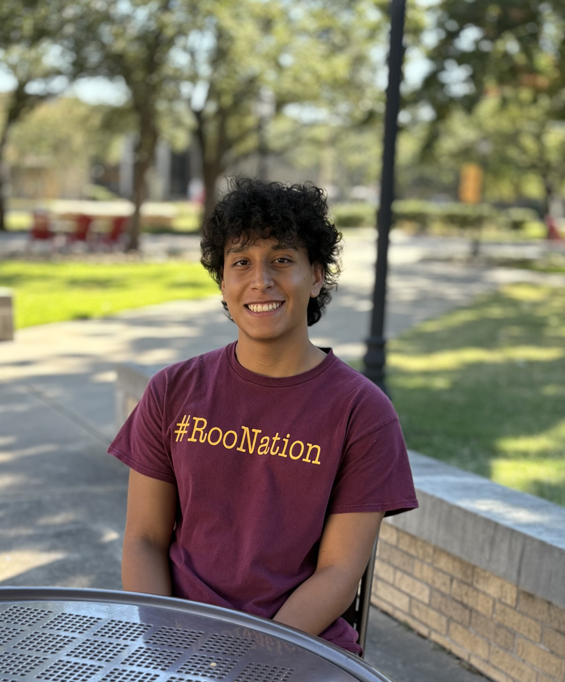 Alex sitting at picnic table on campus