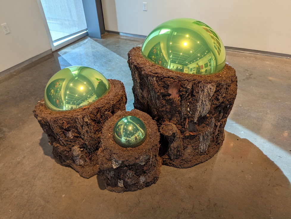 3 tree stumps, each with a green mirror ball on top